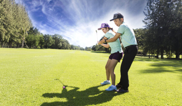 Young female golf player at Driving Range with a Golf Pro