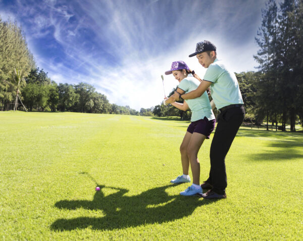 Young female golf player at Driving Range with a Golf Pro